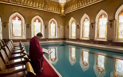 Un joven mormón acerca sus manos a un estanque de bautismo rodeado por hermosas decoraciones del templo