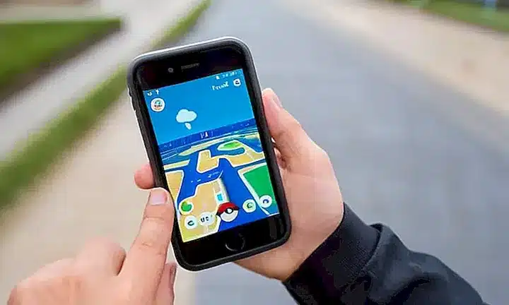 Un niño joven tiene en la mano su smartphone mostrando un PokéStop mientras prepara capturar a uno de estos personajes