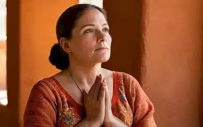 Una anciana latineñita medita quietamente contra un muro de adobe adornado con vidrieras que ilumina su rostro arrugado y vestida con un tradicional huipil