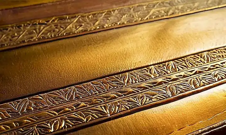 Una antigua biblia con una cubierta de cuero gastada y páginas desteñidas descansa sobre un velador enmarcado por una vista serena distorsionada