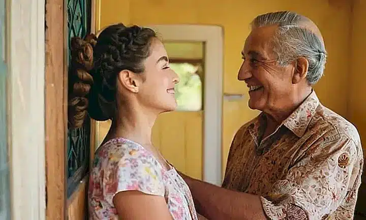 Un anciano serene abraza a una niña con un sonriente gesto maternal