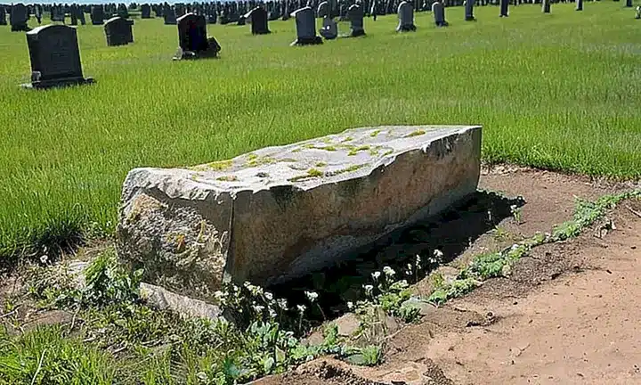 Un antiguo monumento a un difunto se yergue medio enterrado, cubierto de ladrillos, musgo y hieroglficos descomponidos