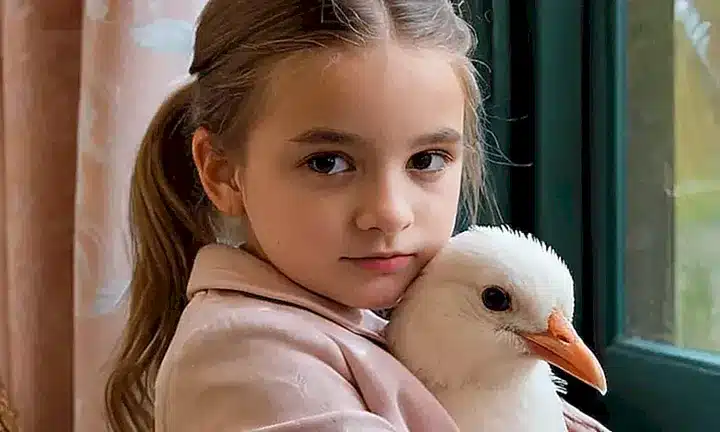 Una joven acaricia un pequeño pájaro blanco llamado Gulliver mientras se baña en la luz cálida de la ventana
