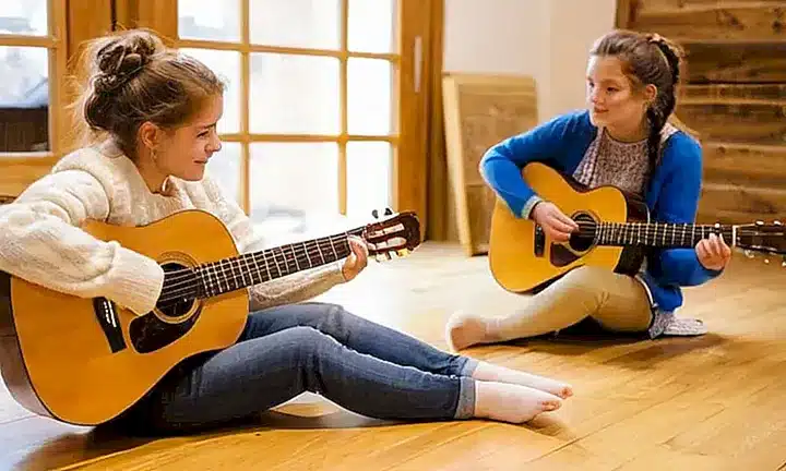 Un grupo de niños con ropa tradicional europea miran una actuación de música acústica en un ambiente cálido y natural