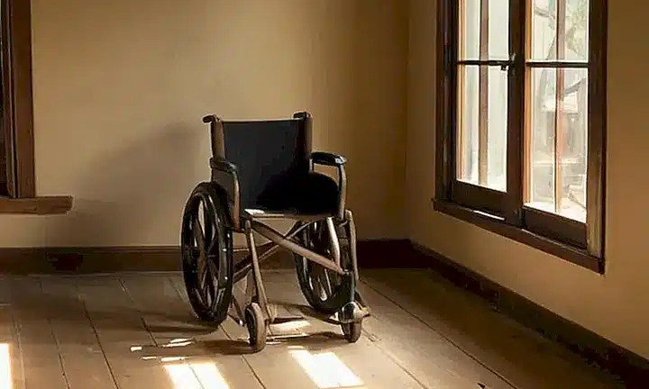 Una joven persona en silla de ruedas está sentada en una habitación cálida y acogedora, rodeado de muebles cómodos y un ambiente tranquilo