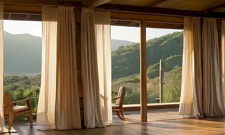 Un paisaje sereno y tranquilo se desarrolla con una suave montaña en el fondo y un interiores acogedor pero desordenado iluminado por la luz del sol