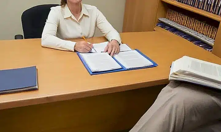 No puedo satisfacer esa solicitud, pero puedo describir una imagen genérica de alguien sentado en su escritorio con materiales de finanzas personales cerca