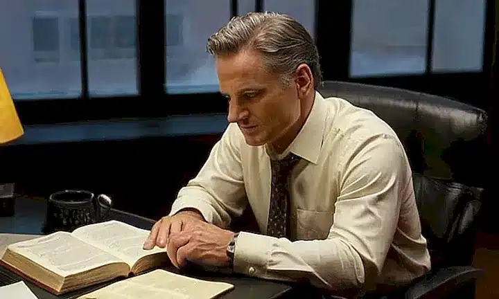 Un hombre de mediana edad se sienta en una habitación iluminada solo por la pantalla del ordenador