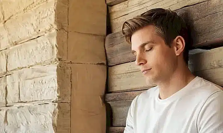 Una ilustración monocromática muestra un joven tranquilo sentado en un banco de madera desgastada