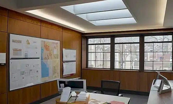 El cuarto es una oficina bien iluminada con muebles y libros sobre arquitectura dispuestos en un armónico orden