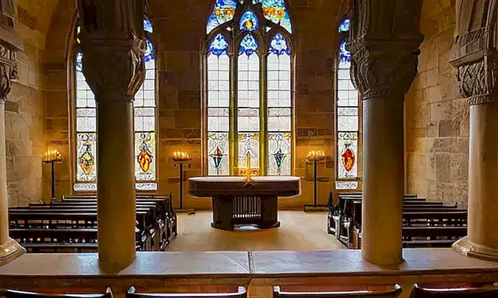 La iglesia está bañada por la luz del sol que pasa a través de las ventanas de vidrio colorado y proyecta sombras en el suelo