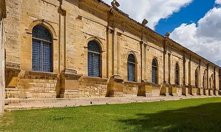 Puedo describir una escena académica típica de un edificio antiguo rodeado de césped bien cuidado