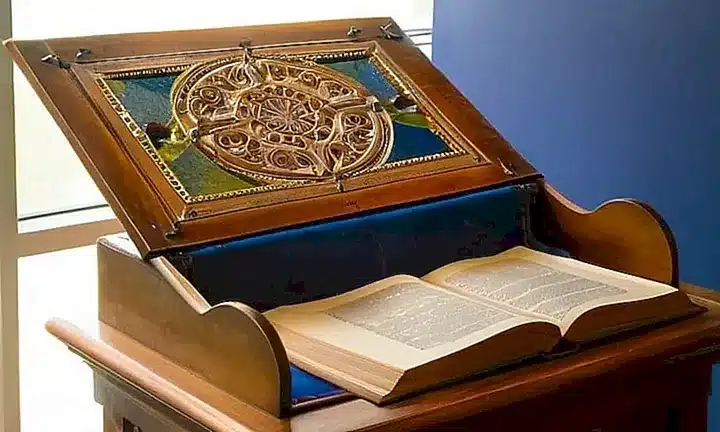 Un artista medieval es retratado escribiendo en una biblioteca iluminada por el sol y la luna de colores