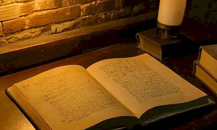 Una habitación anticuada y oscura iluminada débilmente por la luz de una lámpara con un escritor intenso sentado frente a su escritorio