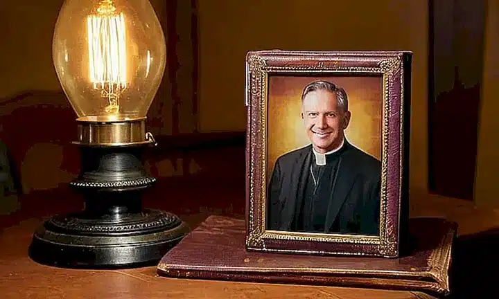 Un antiguo Biblia de cuero marrón descansa en una mesa de madera rodeada de un ambiente acogedor con una placa congelada y una lámpara