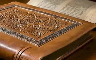 Un libro de cuero dorado descansa sobre una mesa de madera simple bajo un suave resplandor natural