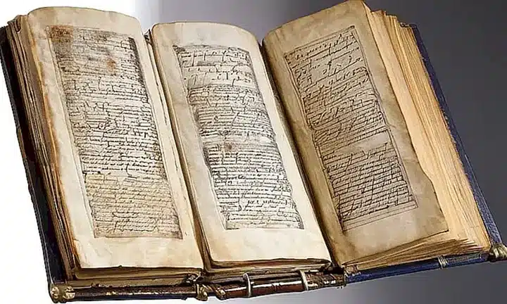 El manuscrito antiguo está desgastado por el tiempo, con paginas amarillentas, laderas gastadas y correas de cuero desgarradas que testimonian su larga historia