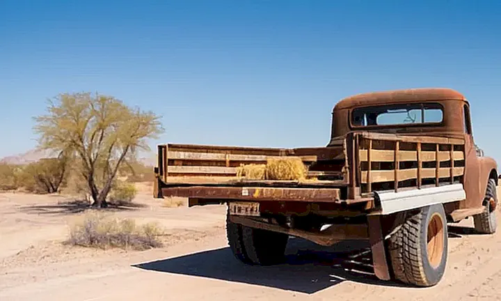 Un viejo camión está en el medio del desierto con un fondo pobre y arruinado