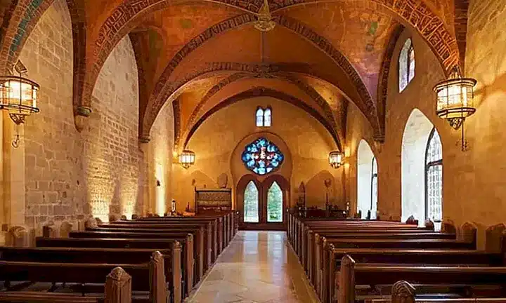 La iglesia presenta una arquitectura hermosa y detallada con elementos de estilo romano, bizantino e islámico que combinan materiales naturales y decoraciones ornamentales para crear un espacio sagrado sereno