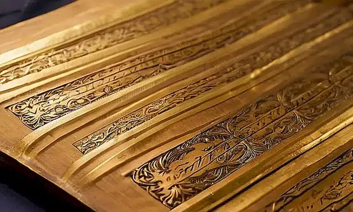 El escrito antiguo reluce bajo la suave luz de una vela encendida con detalles artísticos y ornamentos delicados que sugieren un pasado rico y lejano