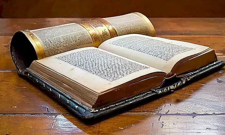 Un antiguo libro reluce en una biblioteca de un monasterio con letras doradas y ilustraciones religiosas que evocan reverencia y historicalidad