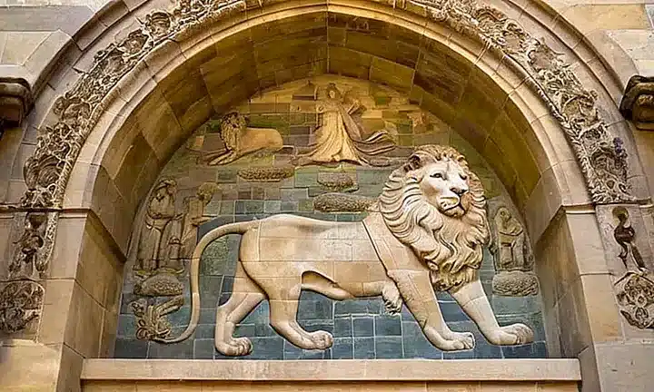 Un muro de granito rodea la figura imponente y majestuosa del dios con detalles intrincados y vibrantes colores a través de las ventanas de vidrieras