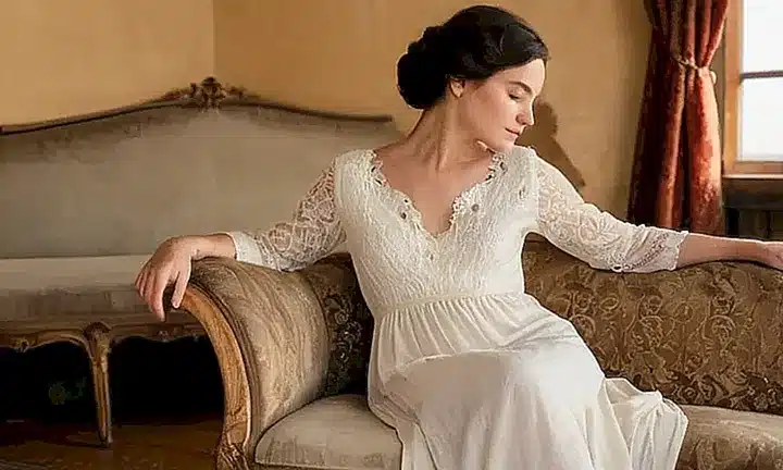 La imagen muestra a una mujer sentada en una silla de madera con la espalda hacia el espectador, rodeada de libros antiguos y objetos decorativos